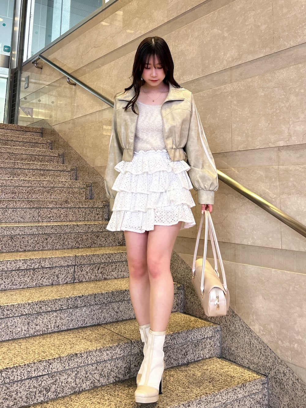 グレー系のブルゾン、ベージュ系のキャミソール、ホワイト系のスカートを着用したレディースの春コーディネートの5枚目の写真