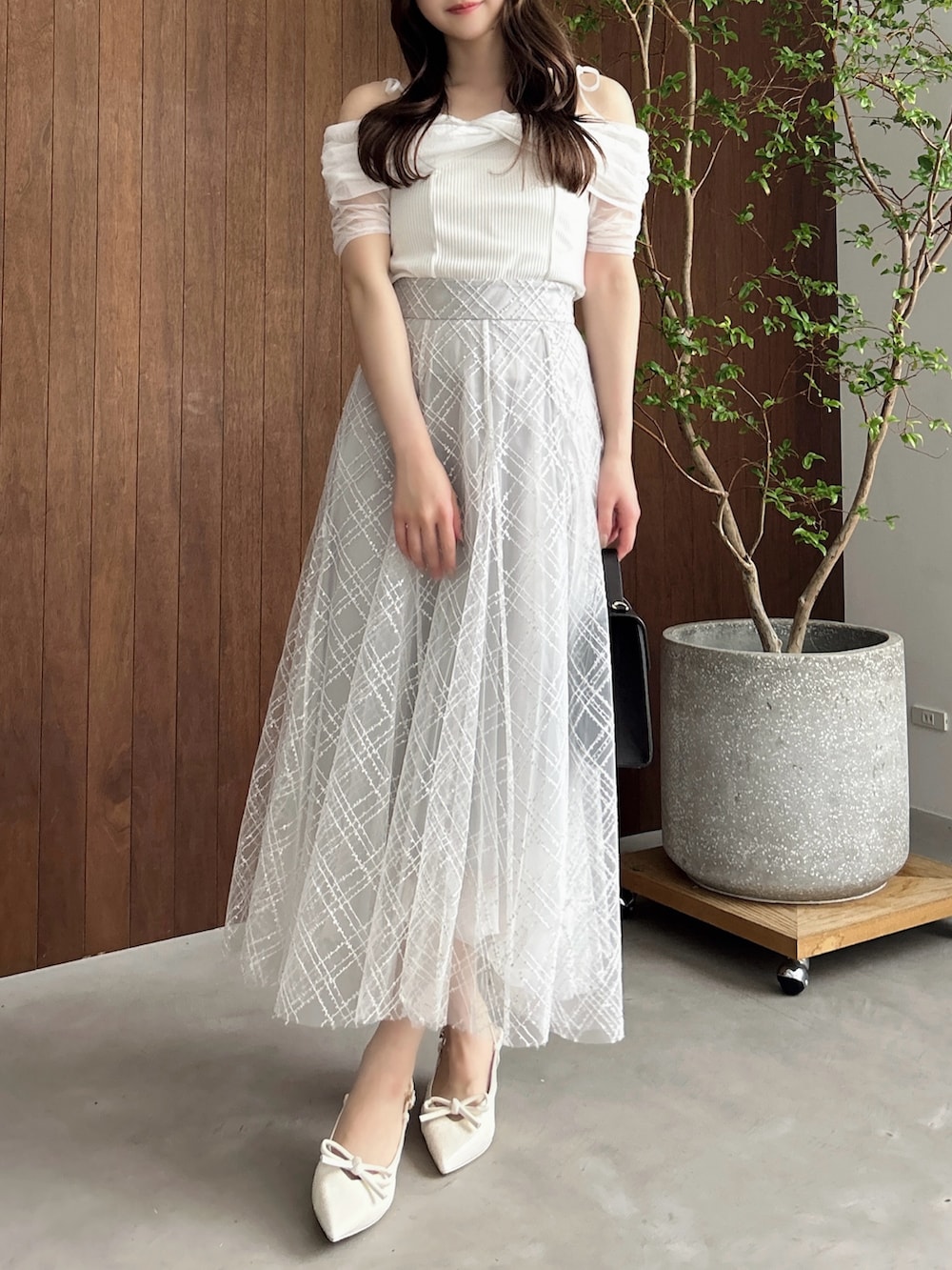 グレー系のスカート、ホワイト系のパンプス、ブラウン系のショルダーバッグを着用したレディースの夏コーディネートの4枚目の写真