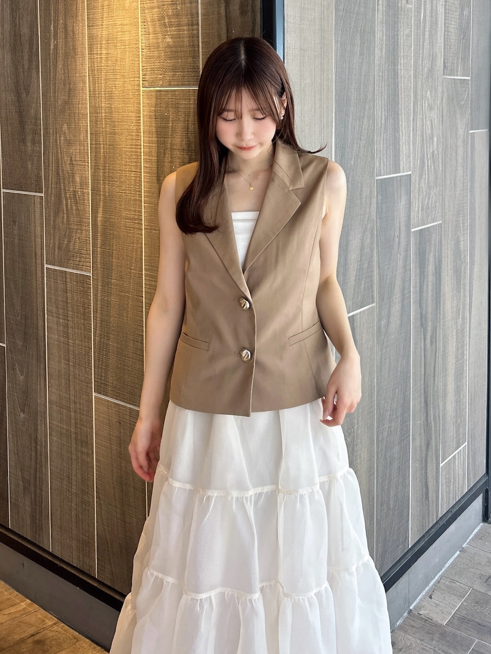 ブラウン系のベスト、ホワイト系のTシャツ/カットソー、ベージュ系のスカートを着用したレディースの秋コーディネートの7枚目の写真