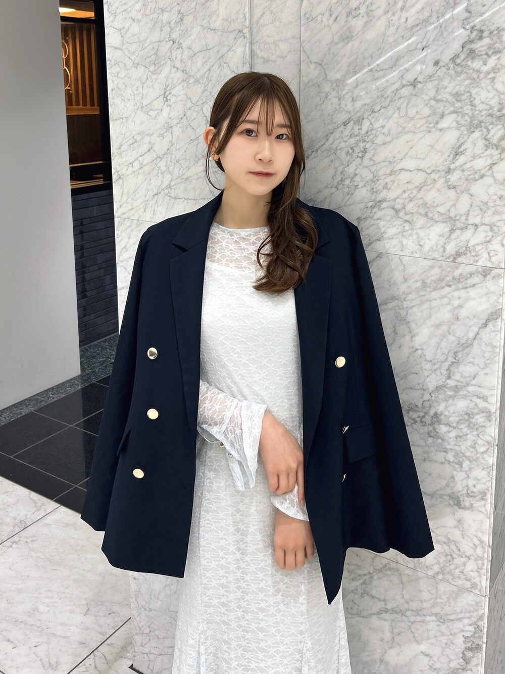 ブルー系のテーラードジャケット、ブルー系のワンピース、ホワイト系のパンプスを着用したレディースの春コーディネートの4枚目の写真