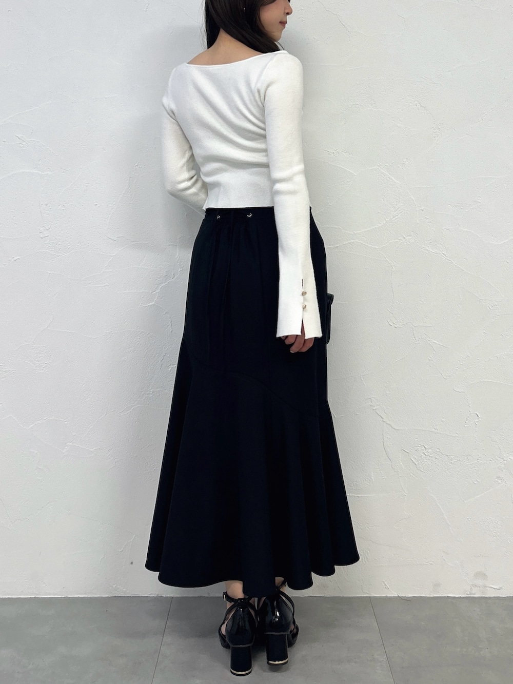 ホワイト系のニット/セーター、ブラック系のスカート、ブラック系のサンダルを着用したレディースの春コーディネートの4枚目の写真