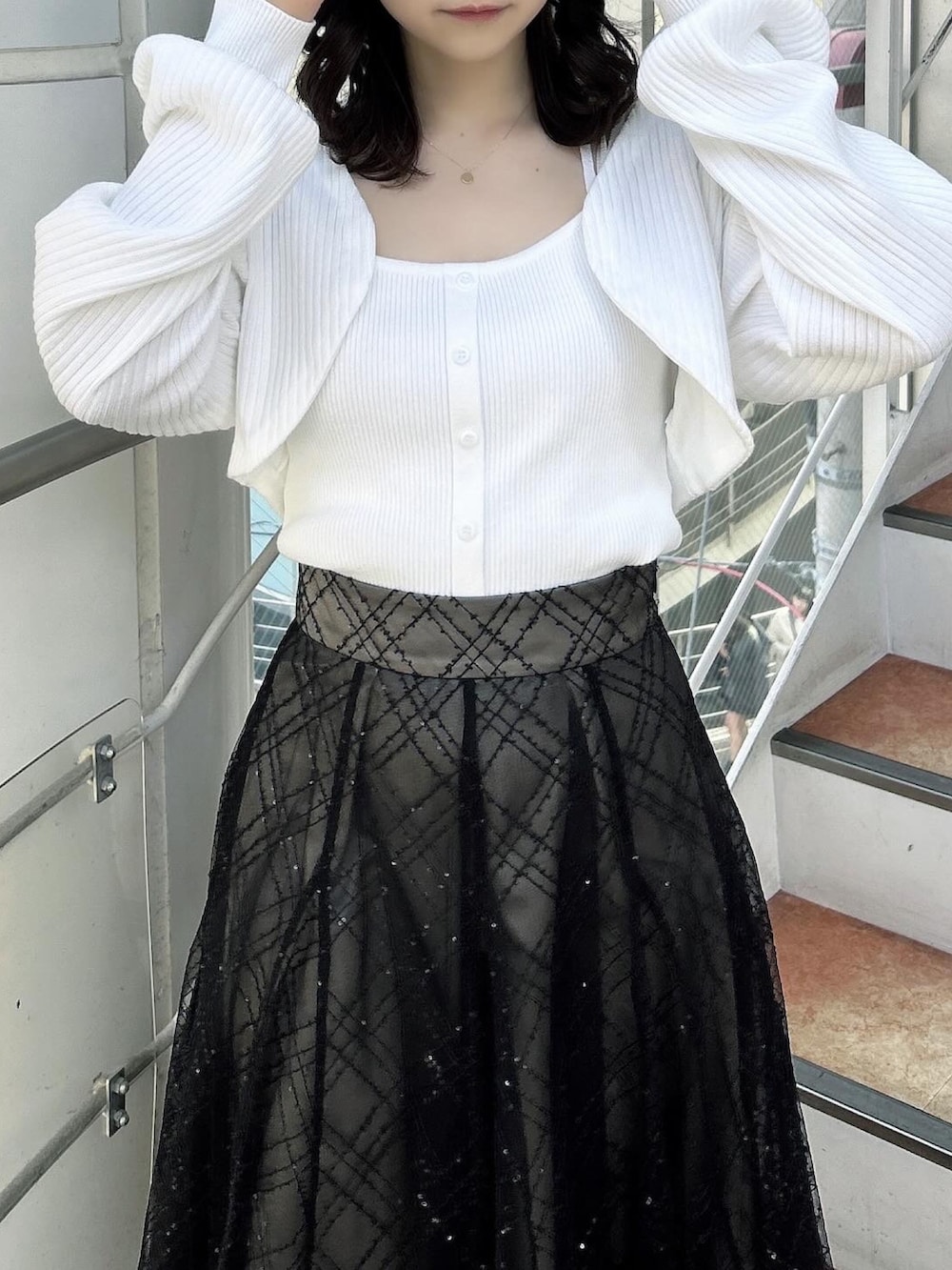 ホワイト系のアンサンブル、ブラック系のスカート、ブラック系のパンプスを着用したレディースの春コーディネートの7枚目の写真