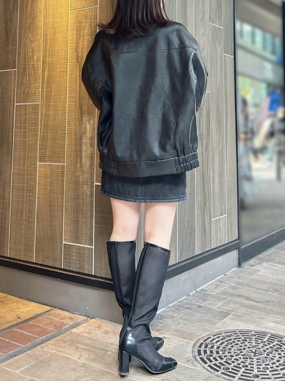 ブラック系のブルゾン、ブラック系のワンピース、ブラック系のブーツを着用したレディースの春コーディネートの3枚目の写真