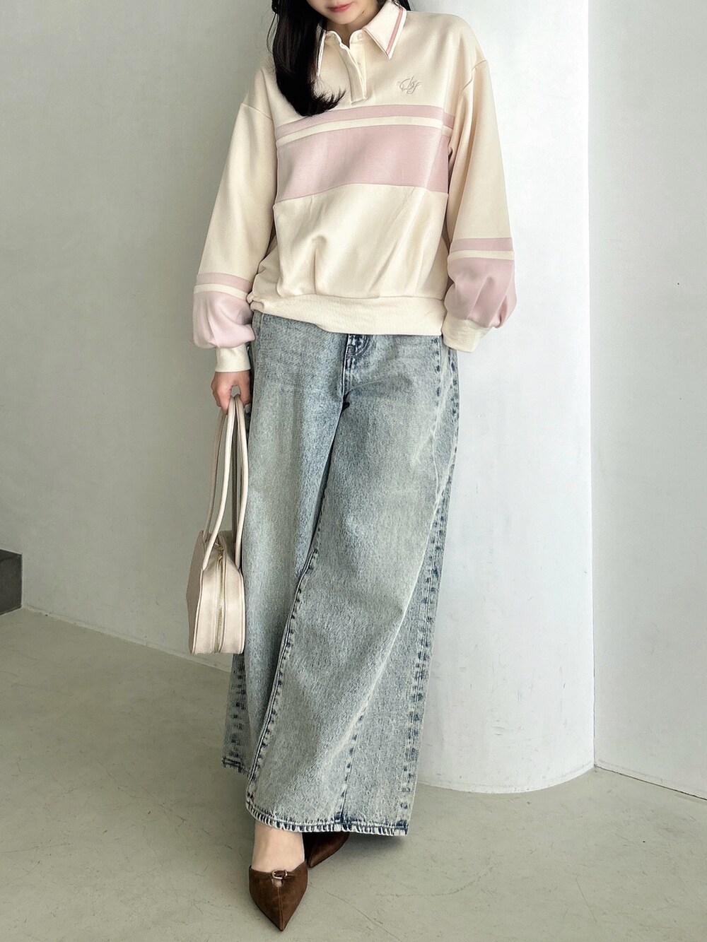 ブルー系のデニムパンツ、ホワイト系のハンドバッグ、ピンク系のスウェットを着用したレディースの冬コーディネートの3枚目の写真
