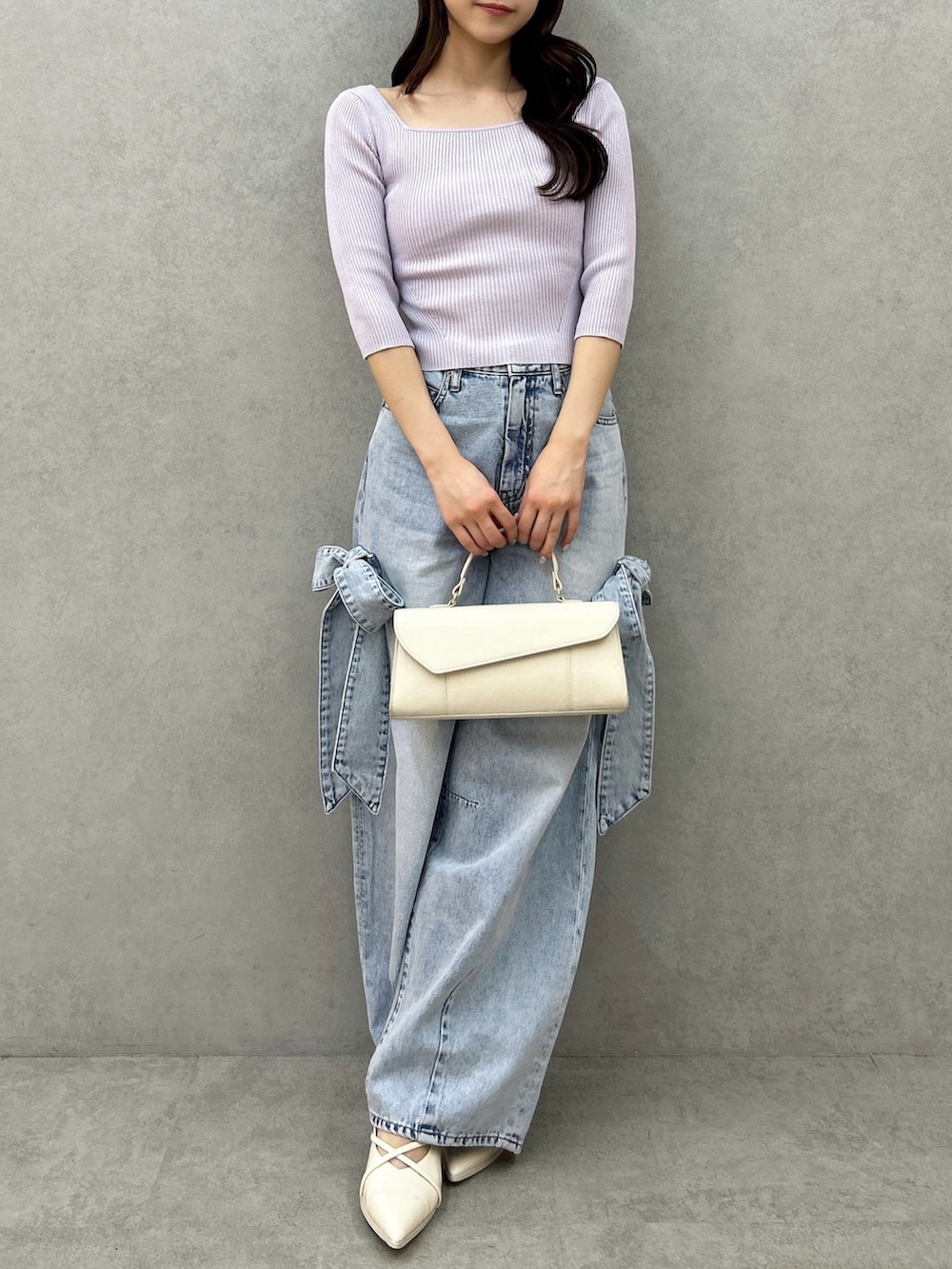 パープル系のニット/セーター、ブルー系のデニムパンツ、ホワイト系のパンプスを着用したレディースの冬コーディネートの2枚目の写真