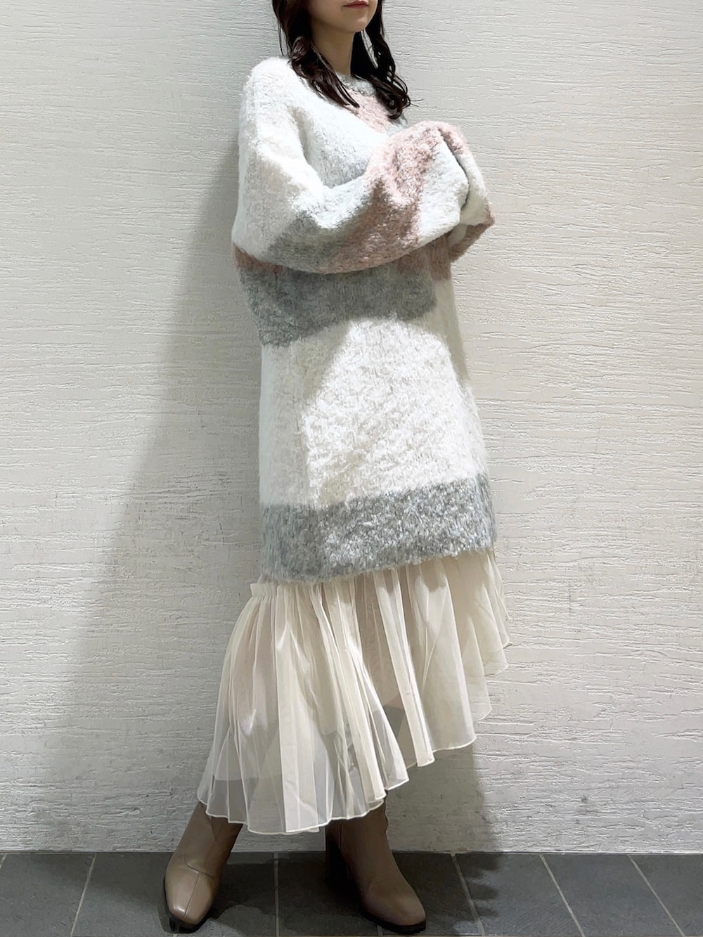 ピンク系のニット/セーター、ホワイト系のスカート、ベージュ系のブーツを着用したレディースの冬コーディネートの3枚目の写真
