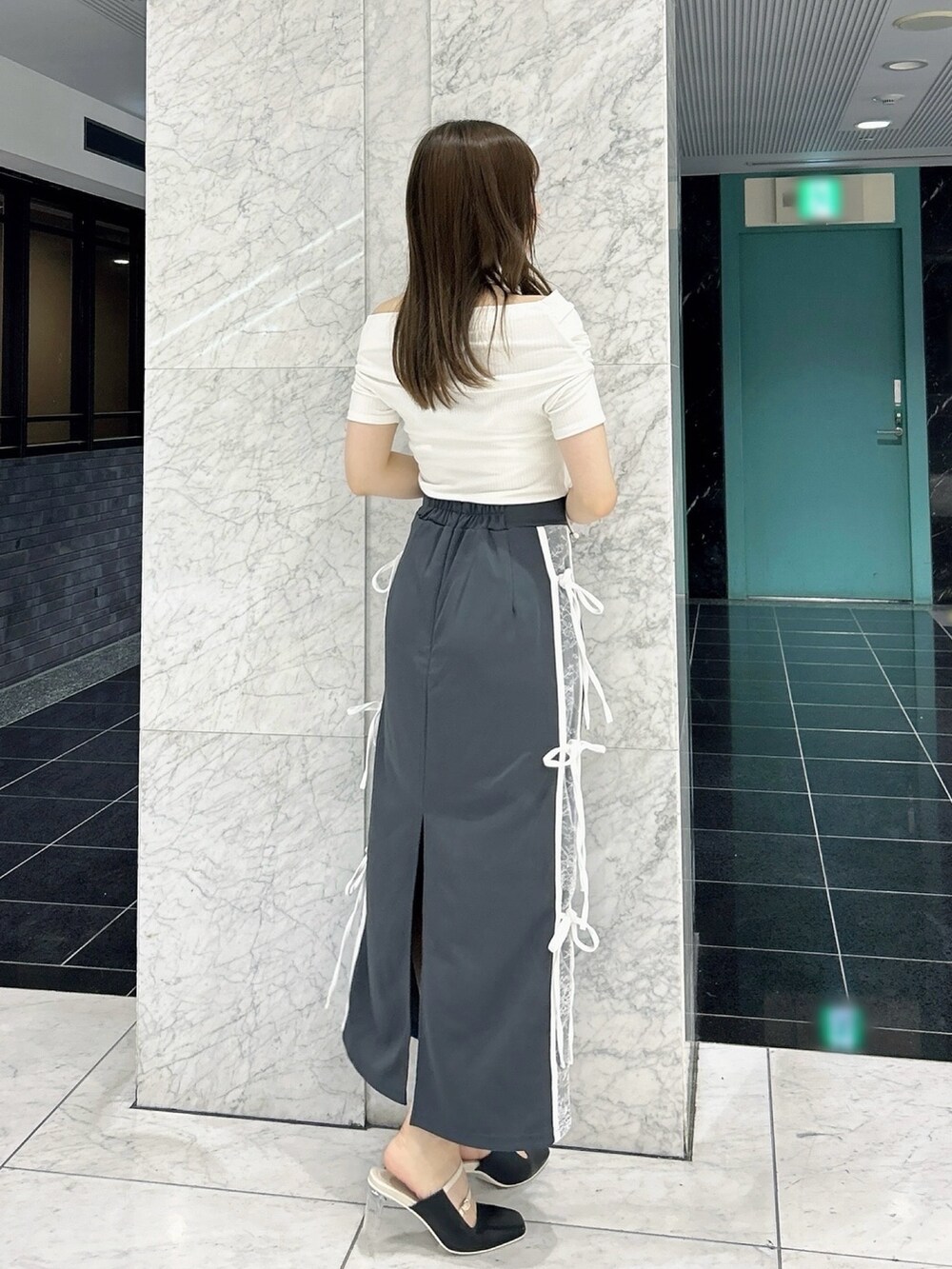 グレー系のスカート、ホワイト系のTシャツ/カットソー、ブラック系のパンプスを着用したレディースの秋コーディネートの5枚目の写真