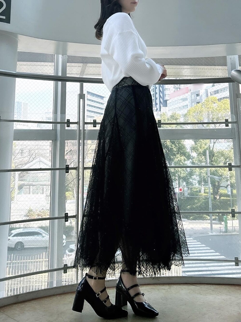 ホワイト系のアンサンブル、ブラック系のスカート、ブラック系のパンプスを着用したレディースの春コーディネートの2枚目の写真