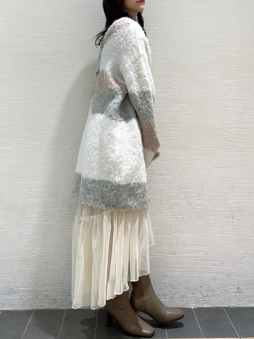 ピンク系のニット/セーター、ホワイト系のスカート、ベージュ系のブーツを着用したレディースの冬コーディネートの4枚目の写真