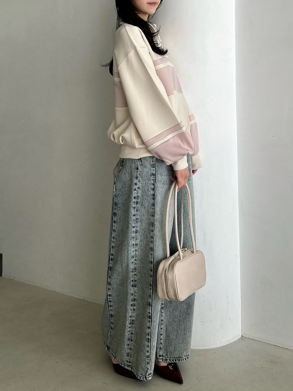 ブルー系のデニムパンツ、ホワイト系のハンドバッグ、ピンク系のスウェットを着用したレディースの冬コーディネートの4枚目の写真