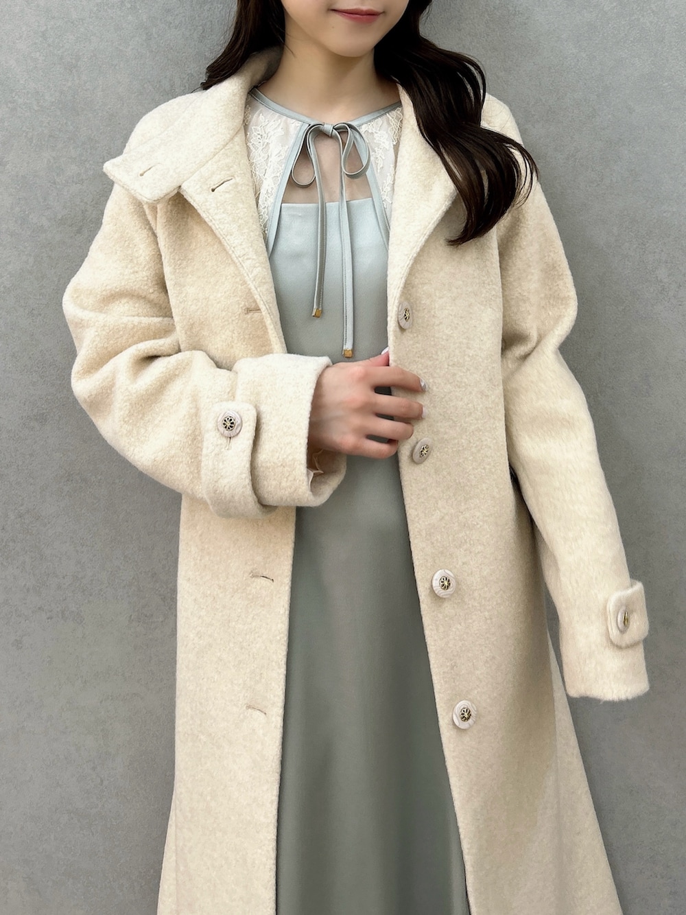 ホワイト系のその他アウター、グリーン系のドレス、ホワイト系のパンプスを着用したレディースの冬コーディネートの6枚目の写真