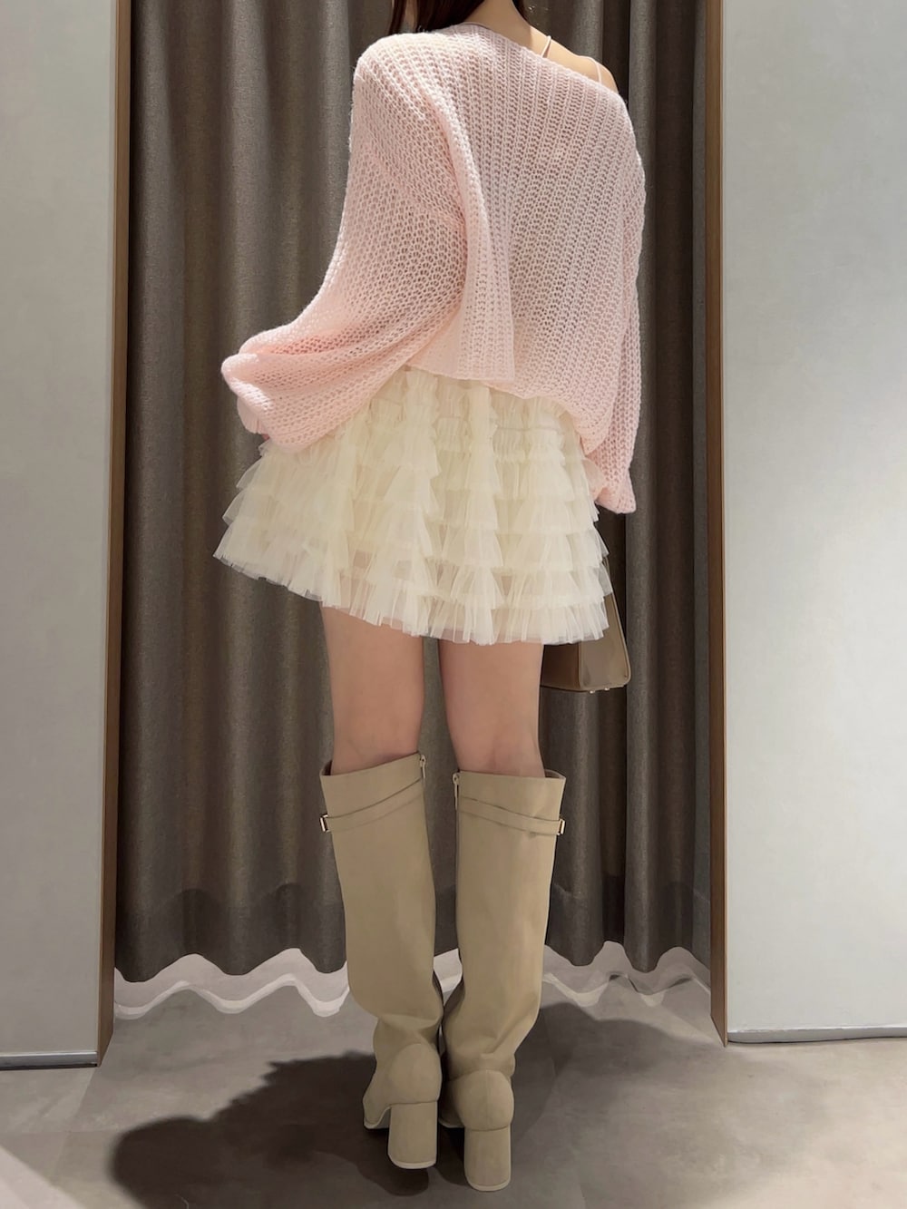 ピンク系のニット/セーター、ホワイト系のスカート、ホワイト系のブーツを着用したレディースの秋コーディネートの5枚目の写真