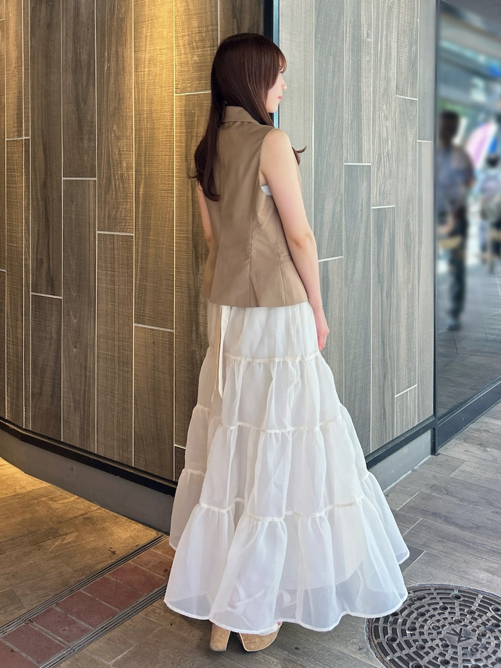 ブラウン系のベスト、ホワイト系のTシャツ/カットソー、ベージュ系のスカートを着用したレディースの秋コーディネートの5枚目の写真