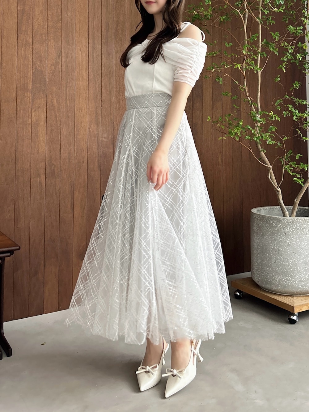 グレー系のスカート、ホワイト系のパンプス、ブラウン系のショルダーバッグを着用したレディースの夏コーディネートの5枚目の写真