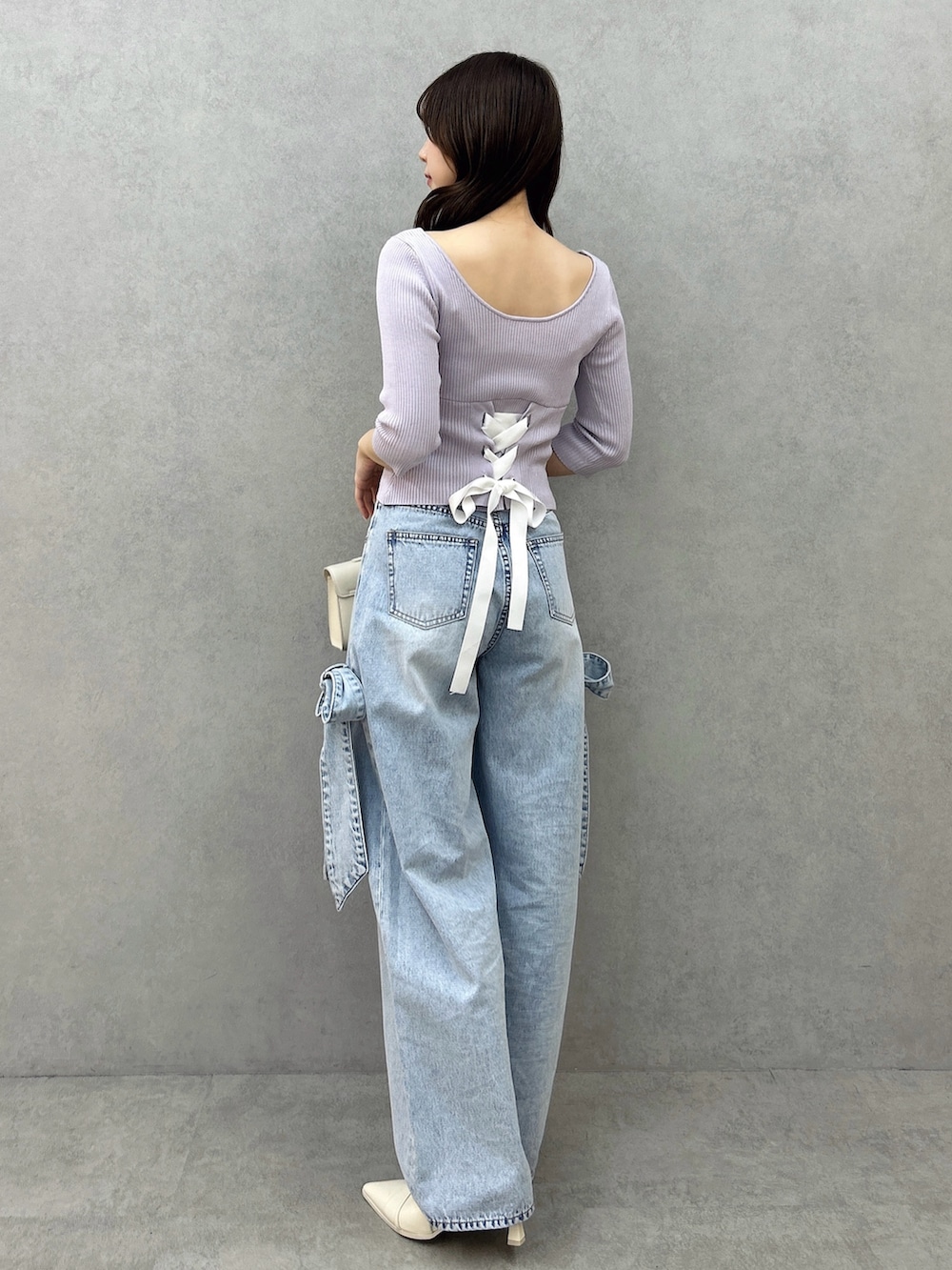 パープル系のニット/セーター、ブルー系のデニムパンツ、ホワイト系のパンプスを着用したレディースの冬コーディネートの5枚目の写真