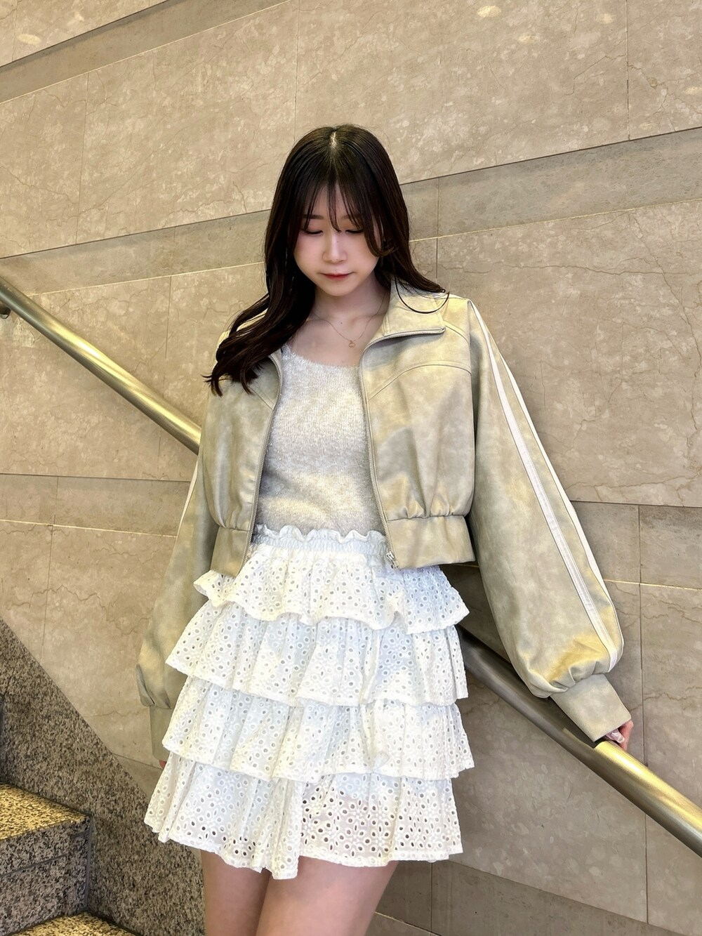 グレー系のブルゾン、ベージュ系のキャミソール、ホワイト系のスカートを着用したレディースの春コーディネートの9枚目の写真