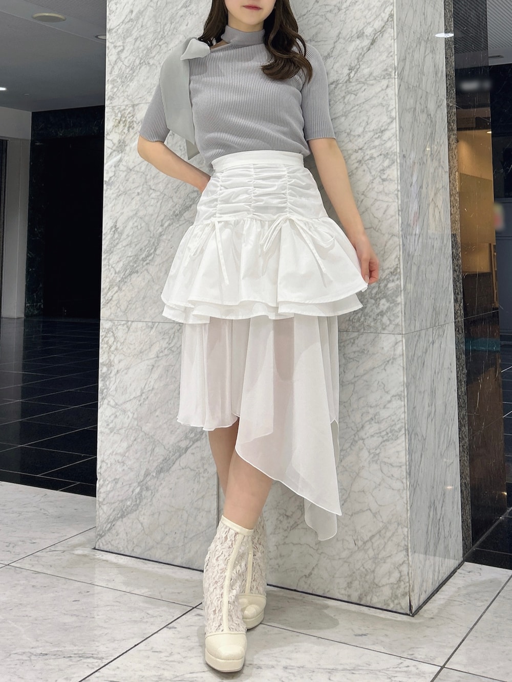 グレー系のニット/セーター、ホワイト系のスカート、ホワイト系のブーツを着用したレディースの春コーディネートの3枚目の写真