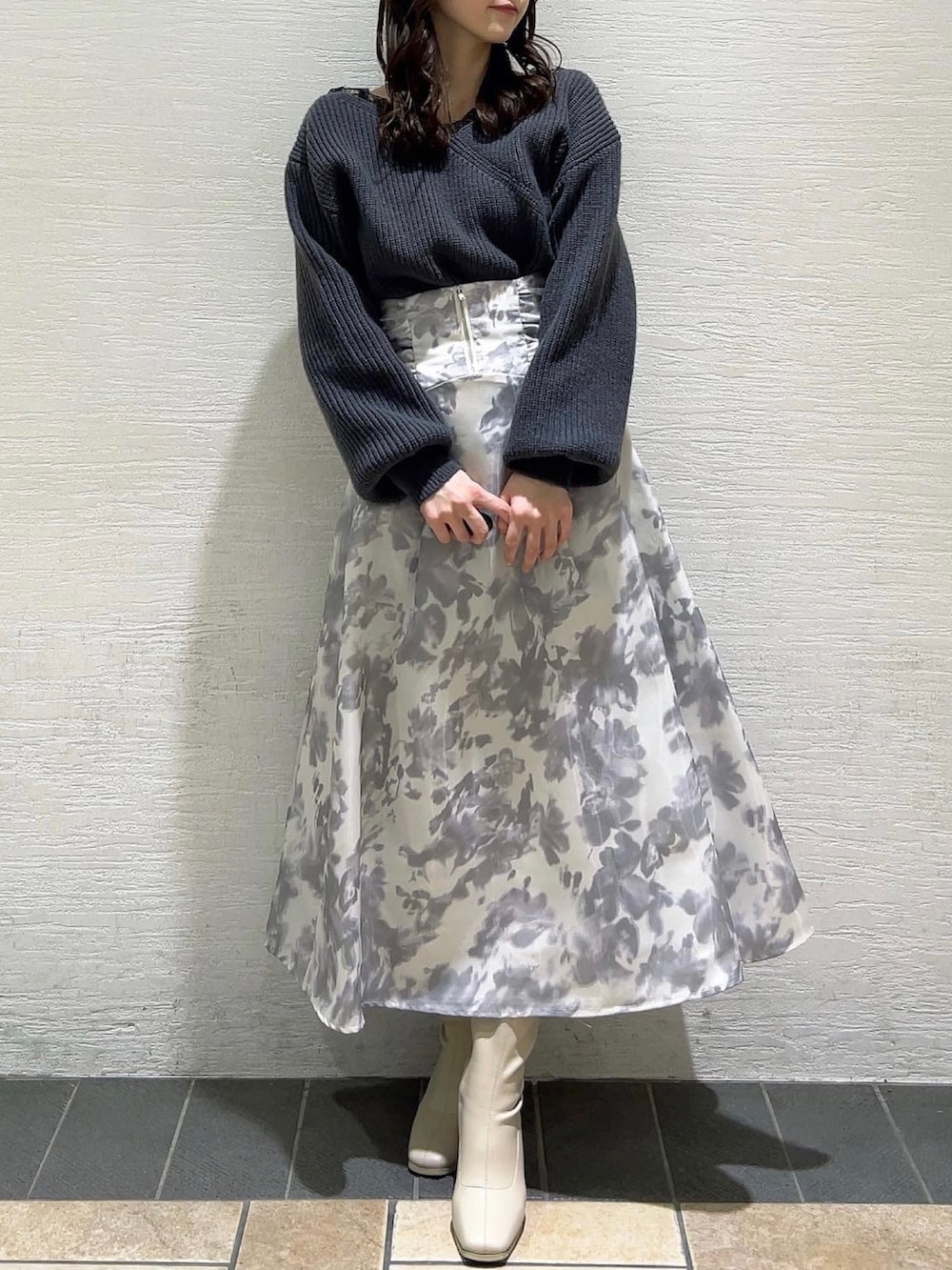 ホワイト系のスカート、ホワイト系のブーツ、グレー系のニット/セーターを着用したレディースの冬コーディネートの2枚目の写真