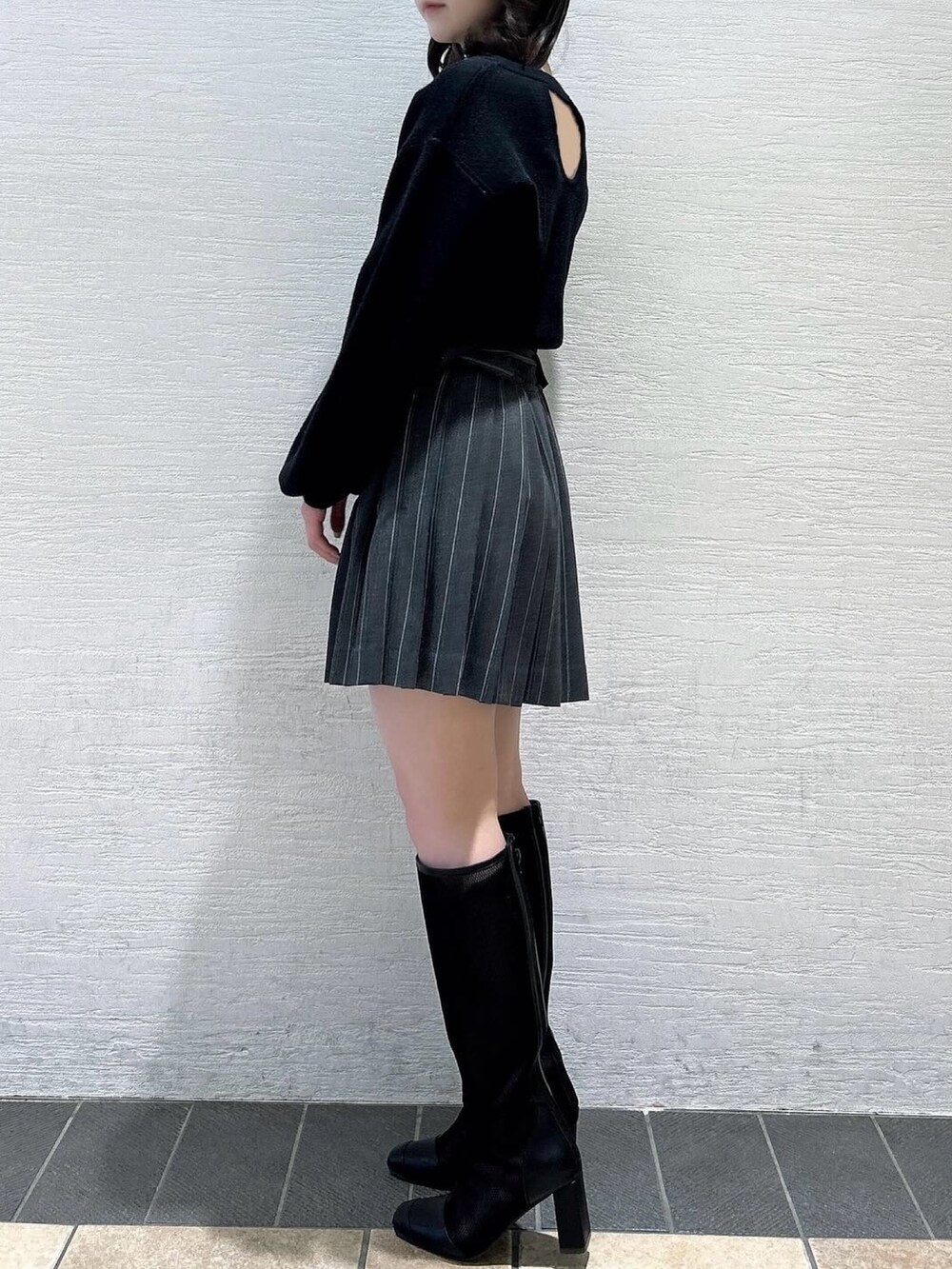 ブラック系のニット/セーター、グレー系のスカート、ブラック系のブーツを着用したレディースの春コーディネートの4枚目の写真