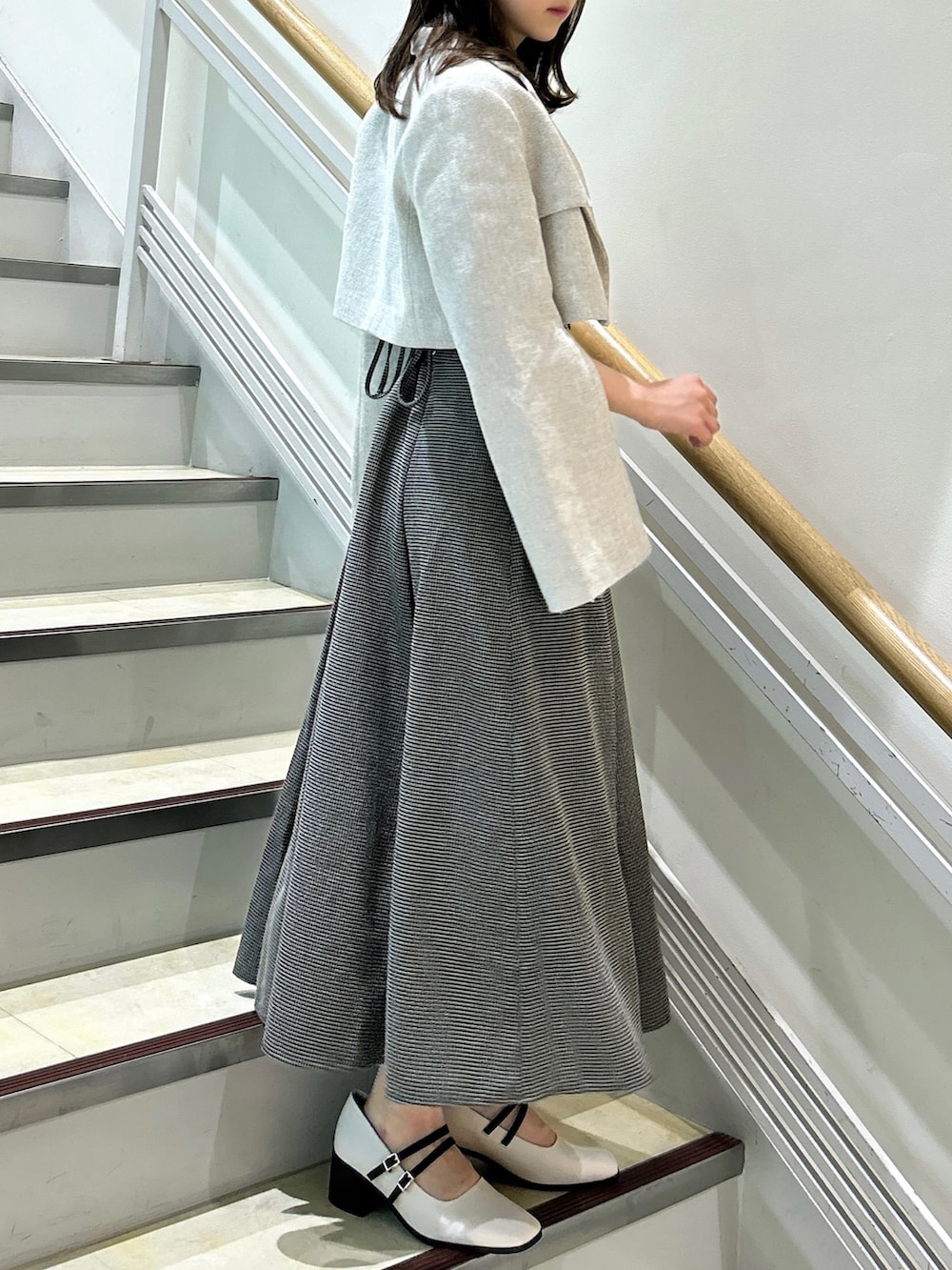 ブラウン系のワンピース、ホワイト系のテーラードジャケット、ベージュ系のパンプスを着用したレディースの秋コーディネートの4枚目の写真