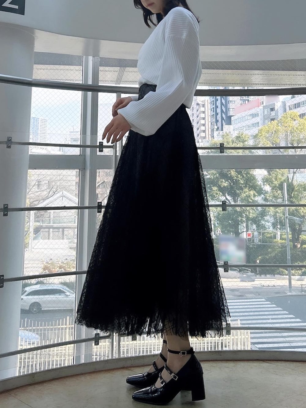 ホワイト系のアンサンブル、ブラック系のスカート、ブラック系のパンプスを着用したレディースの春コーディネートの5枚目の写真