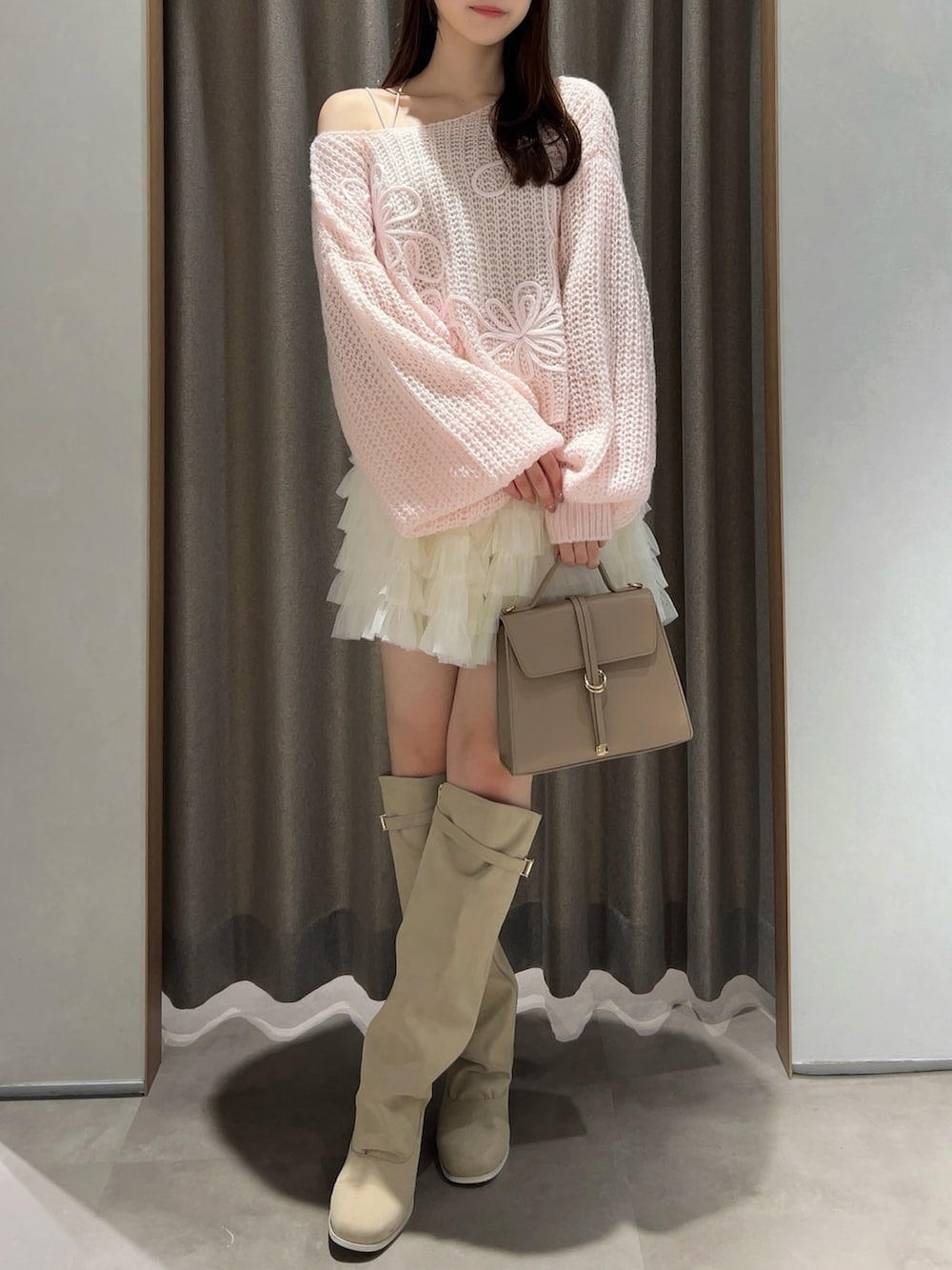 ピンク系のニット/セーター、ホワイト系のスカート、ホワイト系のブーツを着用したレディースの秋コーディネートの2枚目の写真