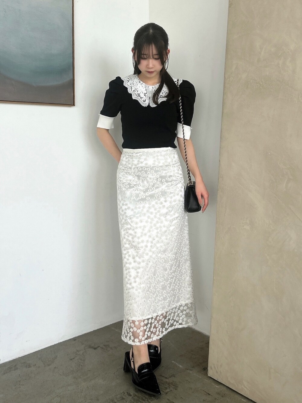 ホワイト系のスカート、ブラック系のニット/セーター、ブラック系のローファーを着用したレディースの春コーディネートの4枚目の写真