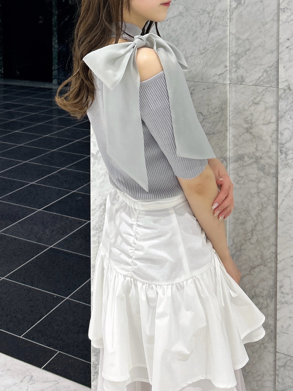 グレー系のニット/セーター、ホワイト系のスカート、ホワイト系のブーツを着用したレディースの春コーディネートの8枚目の写真