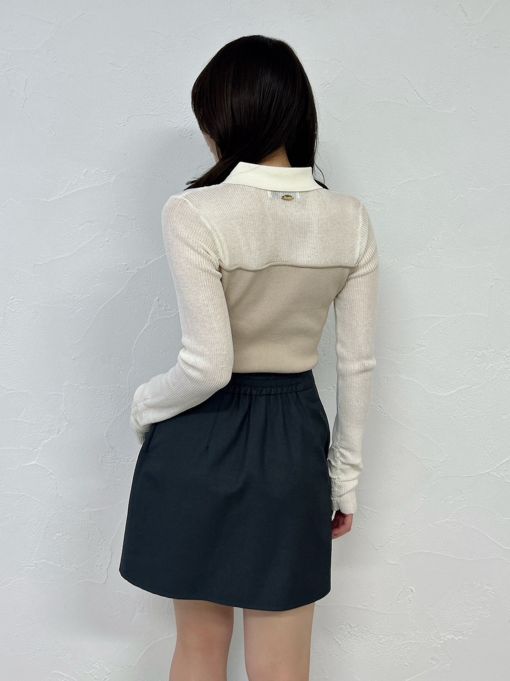 グレー系のスカート、ブラック系のブーツ、ベージュ系のニット/セーターを着用したレディースの春コーディネートの9枚目の写真