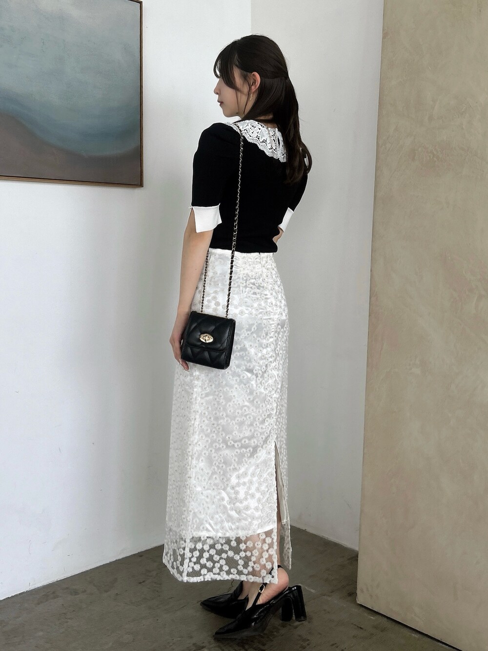 ホワイト系のスカート、ブラック系のニット/セーター、ブラック系のローファーを着用したレディースの春コーディネートの5枚目の写真