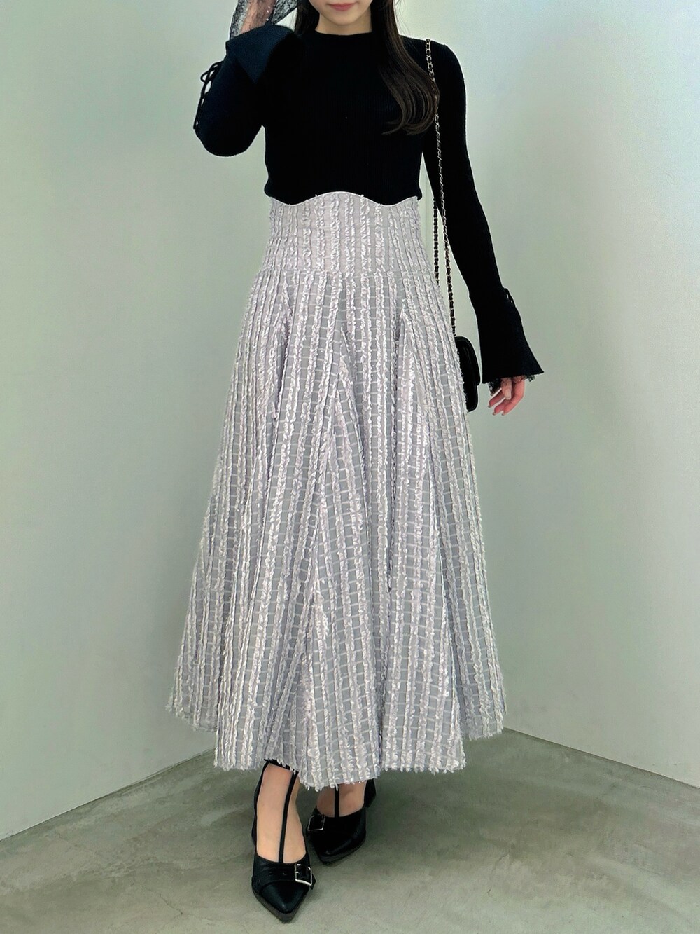 ブラック系のニット/セーター、グレー系のスカート、ブラック系のパンプスを着用したレディースの秋コーディネートの4枚目の写真