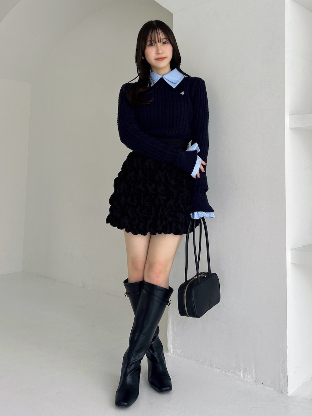 ブラック系のブーツ、ブラック系のスカート、ブルー系のニット/セーターを着用したレディースの冬コーディネートの2枚目の写真