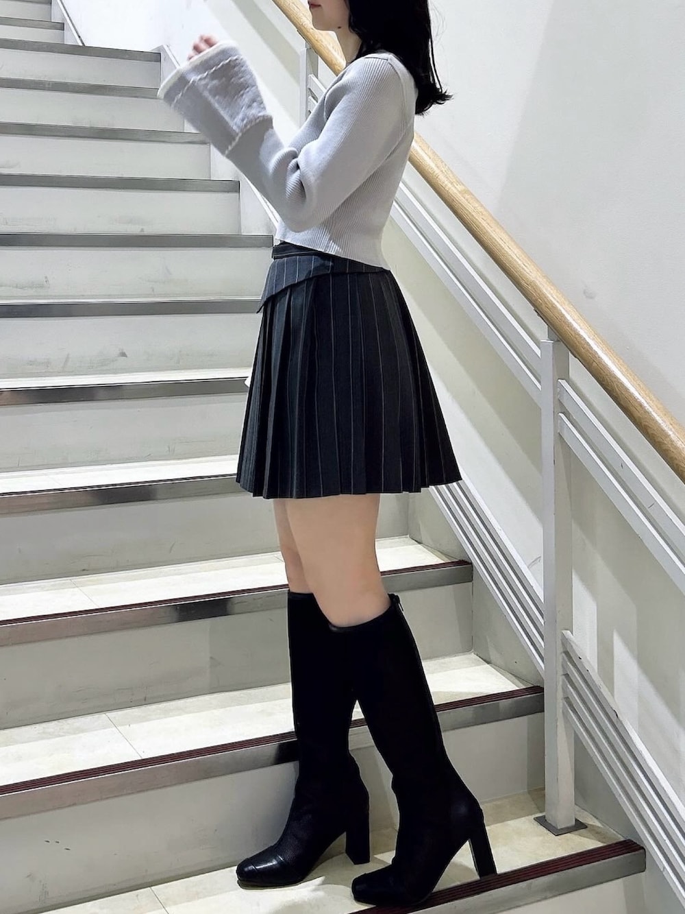 グレー系のニット/セーター、グレー系のスカート、ブラック系のブーツを着用したレディースの冬コーディネートの4枚目の写真