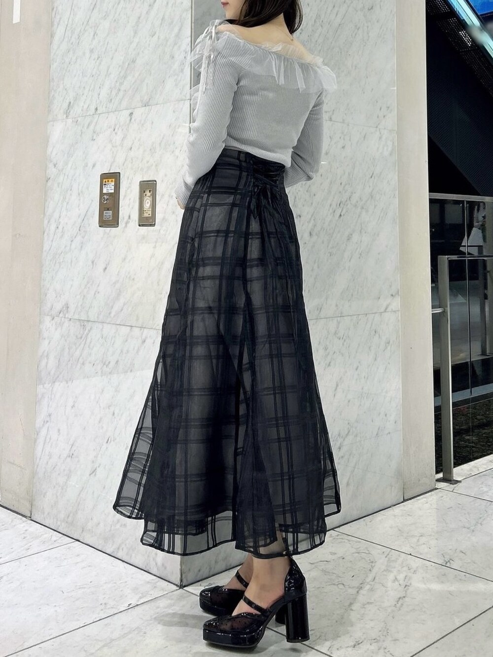 ブラック系のスカート、ブラック系のパンプス、グレー系のニット/セーターを着用したレディースの秋コーディネートの5枚目の写真