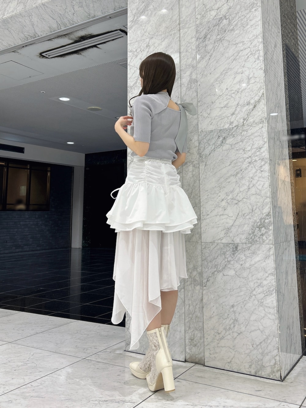 グレー系のニット/セーター、ホワイト系のスカート、ホワイト系のブーツを着用したレディースの春コーディネートの5枚目の写真