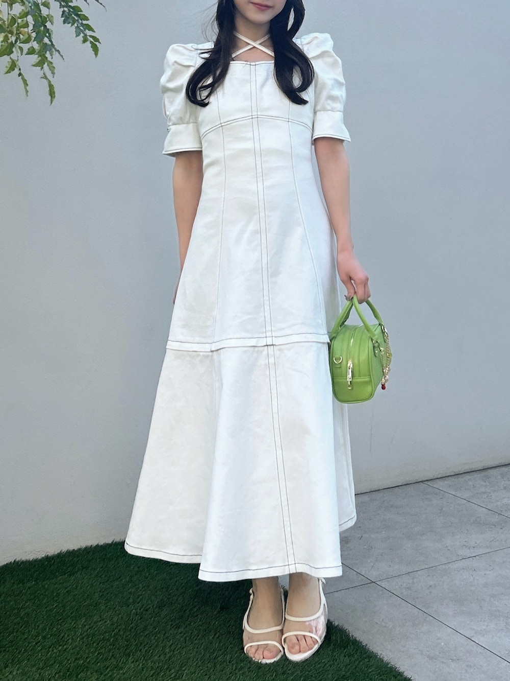 ホワイト系のワンピース、ホワイト系のサンダル、イエロー系のハンドバッグを着用したレディースの春コーディネートの2枚目の写真