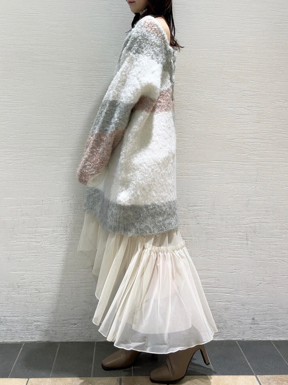 ピンク系のニット/セーター、ホワイト系のスカート、ベージュ系のブーツを着用したレディースの冬コーディネートの5枚目の写真