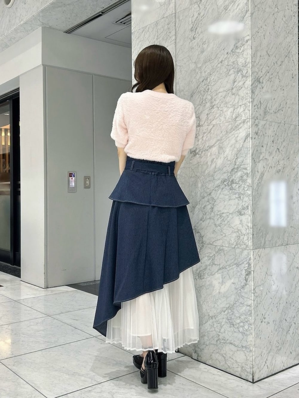 ブルー系のスカート、ブラック系のパンプス、ピンク系のニット/セーターを着用したレディースの秋コーディネートの5枚目の写真