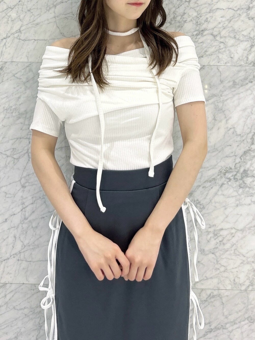 グレー系のスカート、ホワイト系のTシャツ/カットソー、ブラック系のパンプスを着用したレディースの秋コーディネートの6枚目の写真