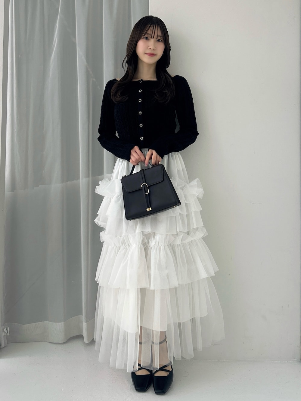 ブラック系のニット/セーター、ホワイト系のスカート、ブラック系のサンダルを着用したレディースの冬コーディネートの4枚目の写真