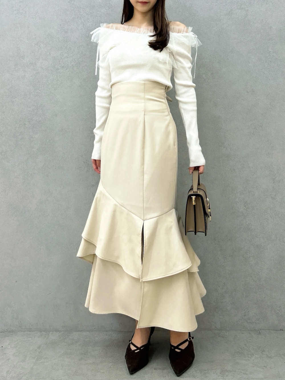 ホワイト系のニット/セーター、ホワイト系のスカート、ブラウン系のパンプスを着用したレディースの秋コーディネートの4枚目の写真