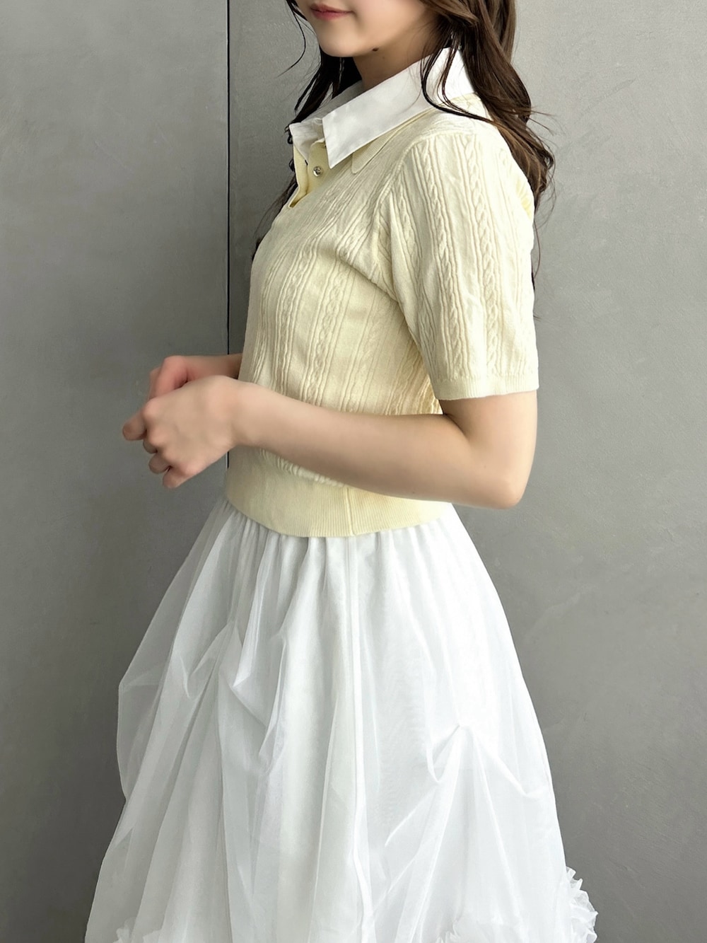 イエロー系のニット/セーター、ホワイト系のスカート、ブラウン系のハンドバッグを着用したレディースの春コーディネートの10枚目の写真