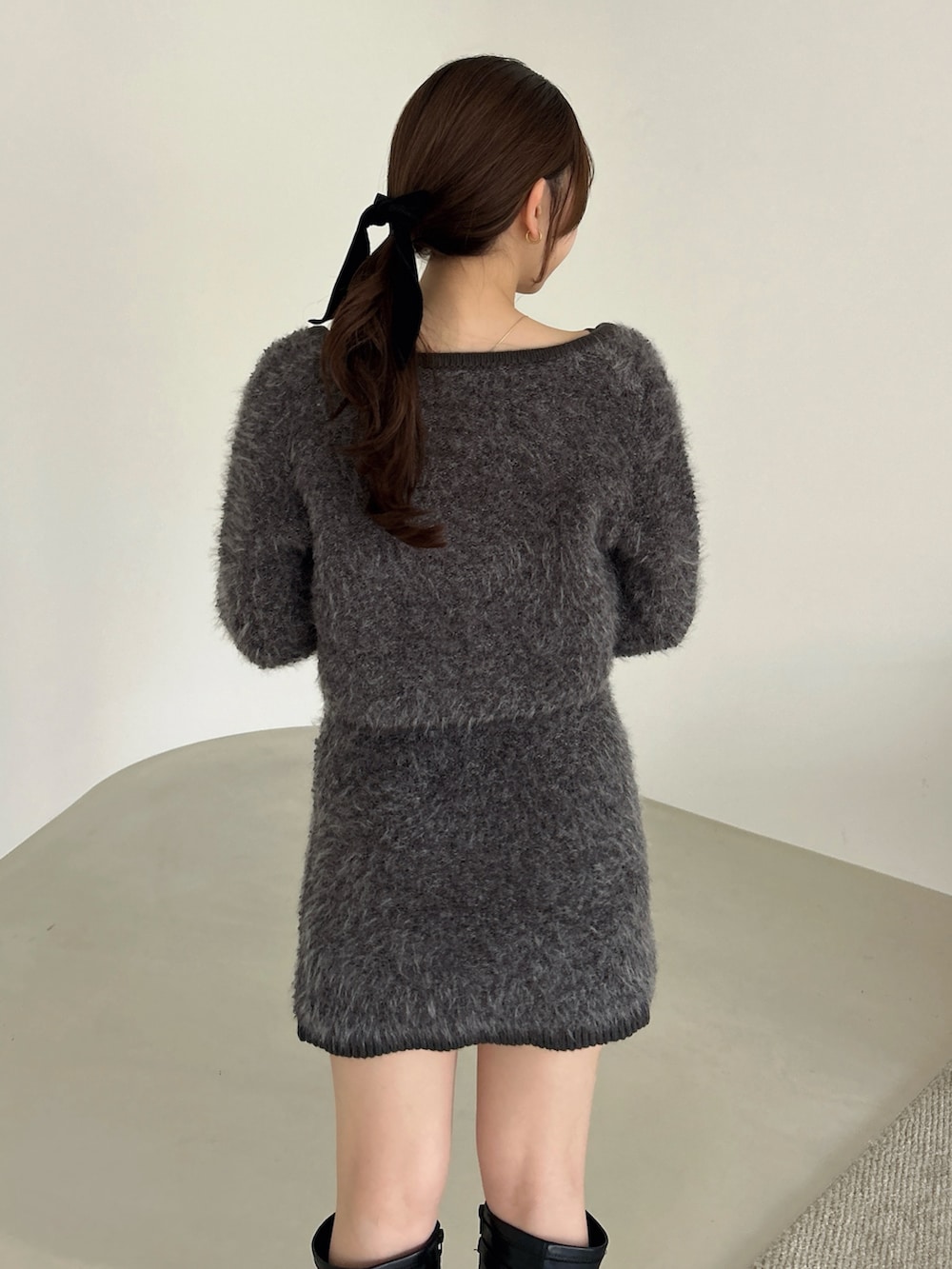 グレー系のノーカラージャケット、グレー系のワンピース、ブラック系のブーツを着用したレディースの冬コーディネートの10枚目の写真