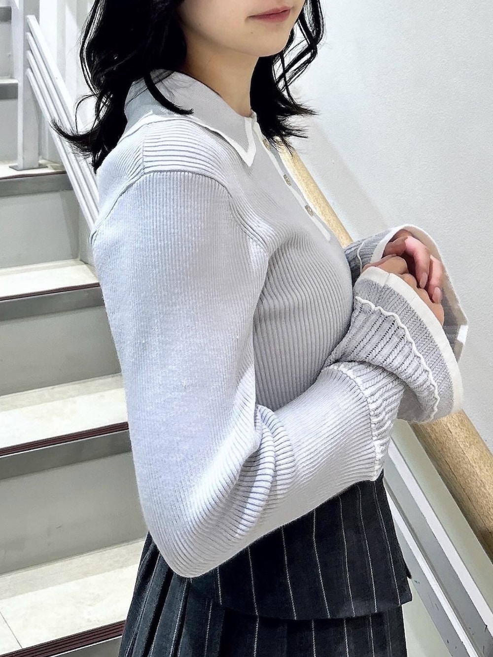 グレー系のニット/セーター、グレー系のスカート、ブラック系のブーツを着用したレディースの冬コーディネートの9枚目の写真