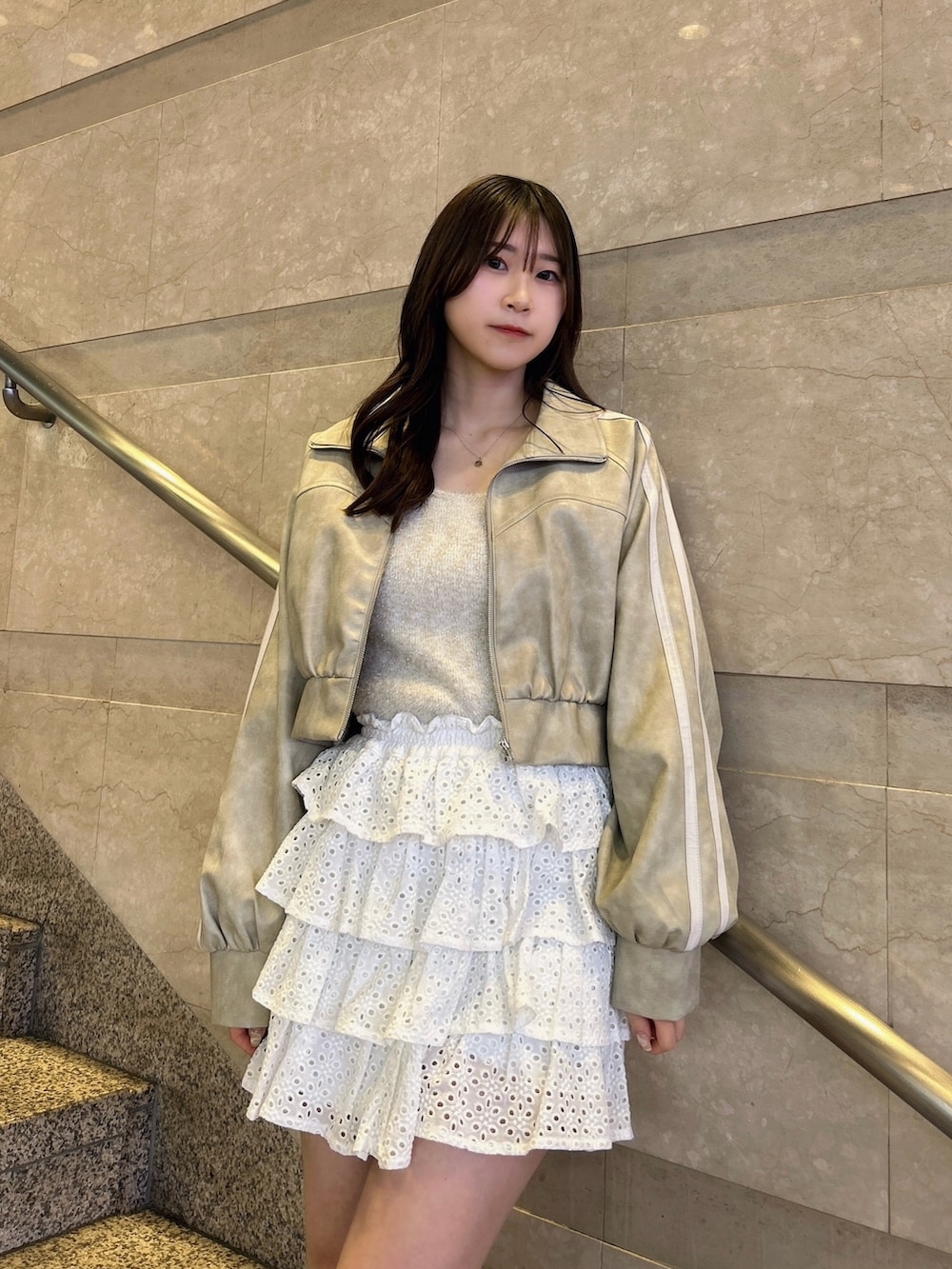 グレー系のブルゾン、ベージュ系のキャミソール、ホワイト系のスカートを着用したレディースの春コーディネートの7枚目の写真