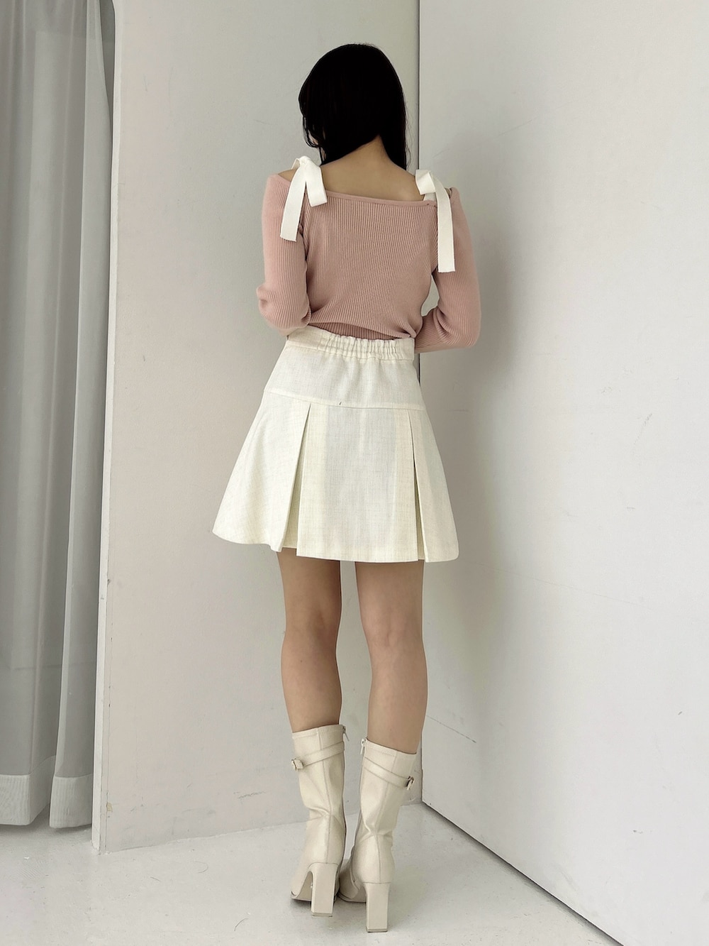 ピンク系のニット/セーター、ホワイト系のスカート、ホワイト系のブーツを着用したレディースの冬コーディネートの5枚目の写真