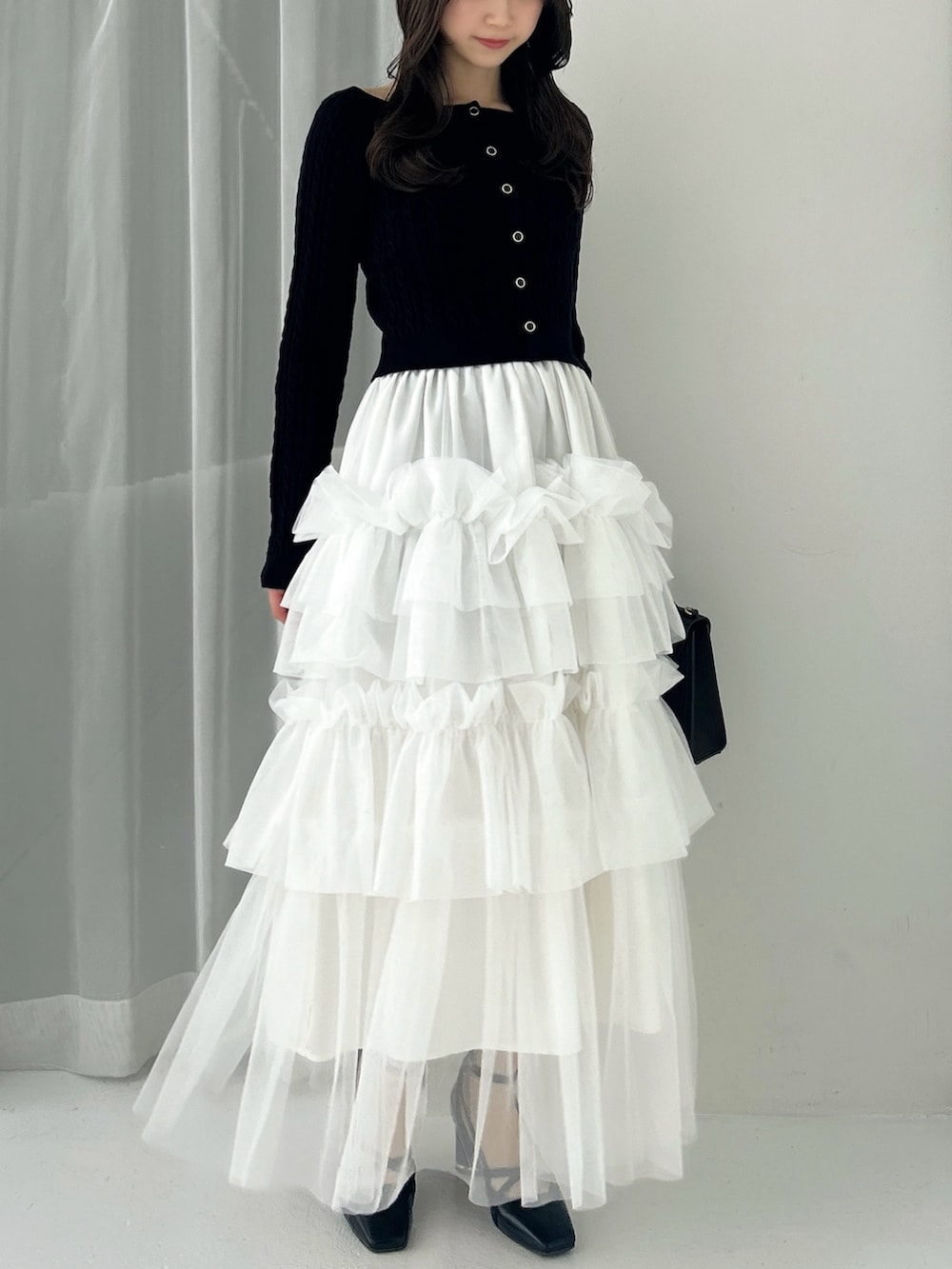 ブラック系のニット/セーター、ホワイト系のスカート、ブラック系のサンダルを着用したレディースの冬コーディネートの2枚目の写真