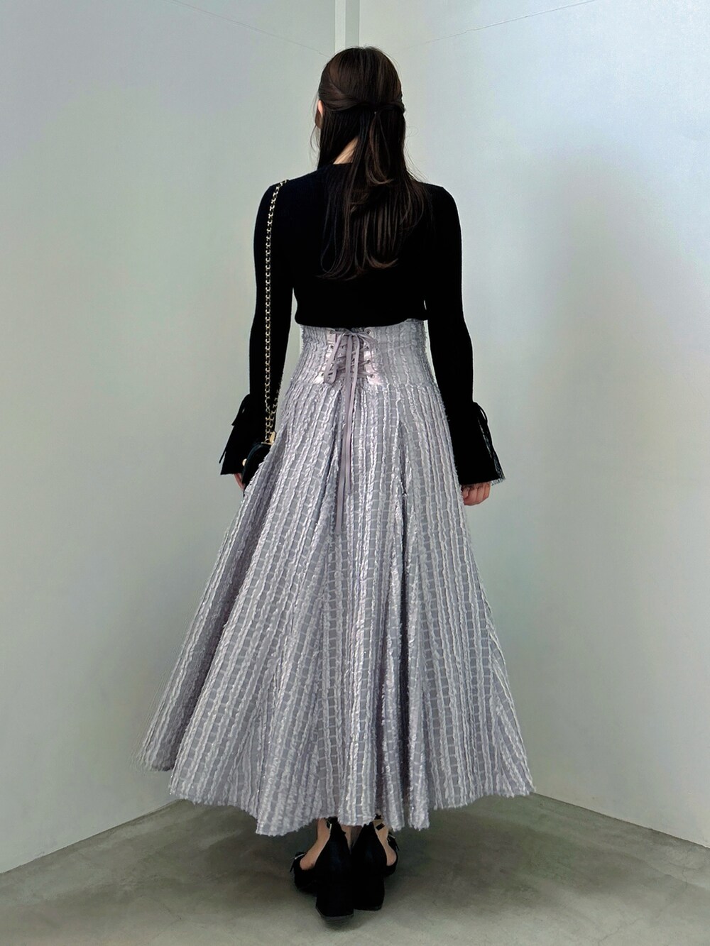 ブラック系のニット/セーター、グレー系のスカート、ブラック系のパンプスを着用したレディースの秋コーディネートの6枚目の写真