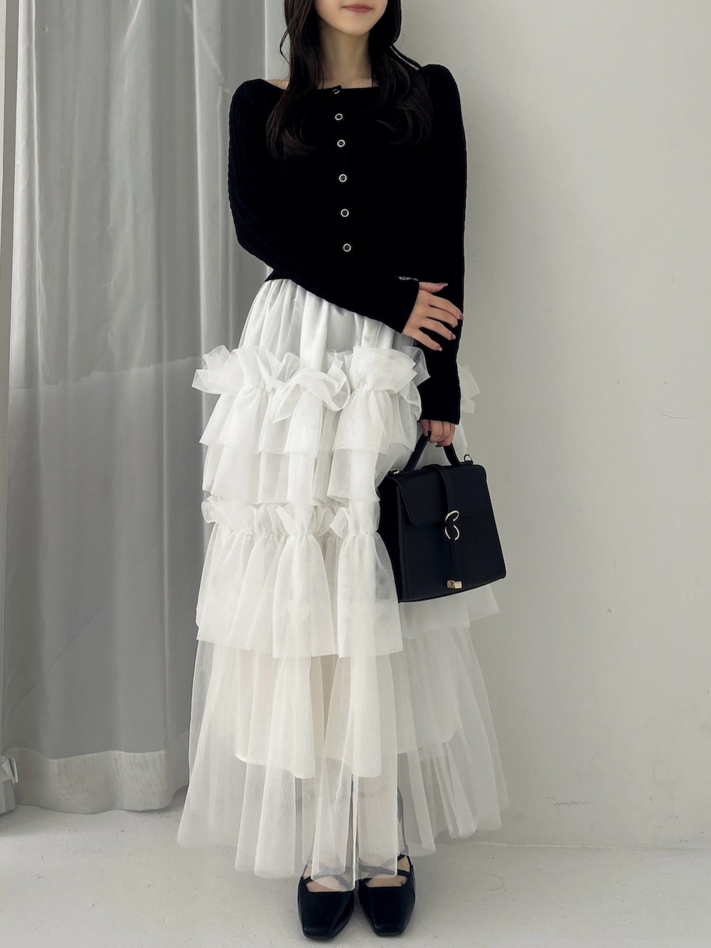 ブラック系のニット/セーター、ホワイト系のスカート、ブラック系のサンダルを着用したレディースの冬コーディネートの3枚目の写真