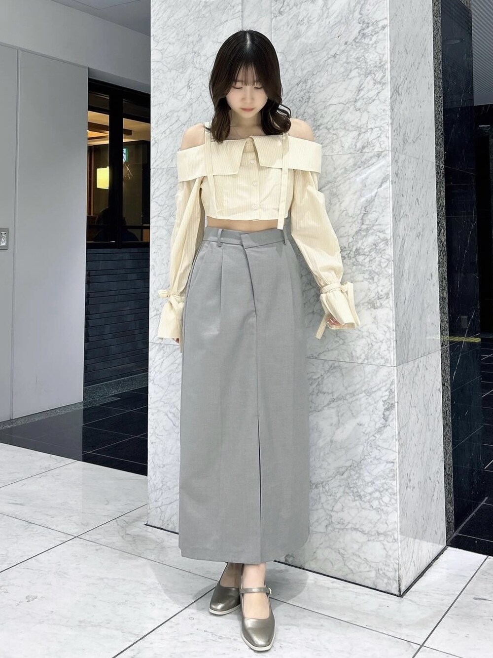 グレー系のスカート、シルバー系のパンプス、イエロー系のシャツ/ブラウスを着用したレディースの春コーディネートの4枚目の写真